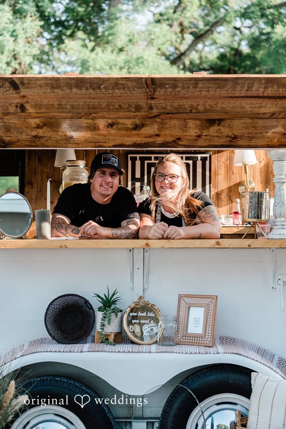 Two bartenders lean out of the horse-trailer bar window, ready to pour for the reception