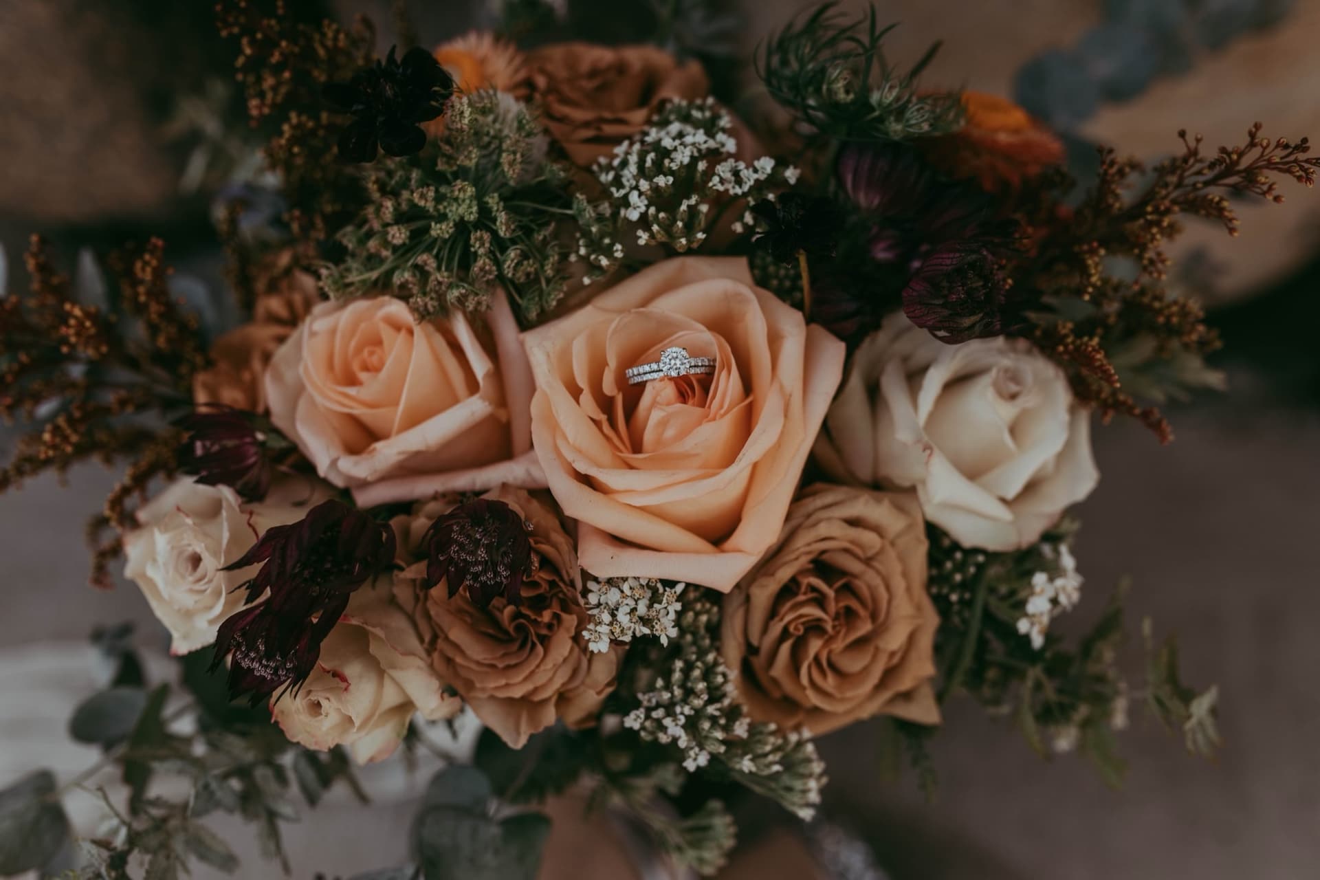 Wedding bands nestled in the petals of a toffee rose at the center of an autumn bouquet, fall barn wedding